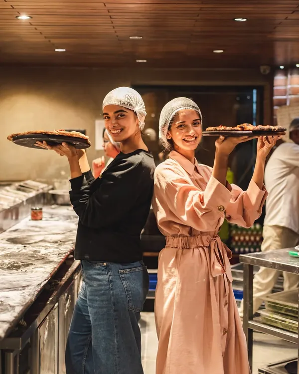 Two happy participants in our pizza making workshop, proudly holding up their finished creations. Making pizza is fun, but eating your own creation is pure love.