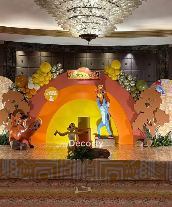 The complete stage setup for a grand 'Lion King' themed birthday party. The scene features a vibrant Pride Rock backdrop, life-sized character models of Mufasa, Pumbaa, and Timon, and themed flooring to create an immersive experience.