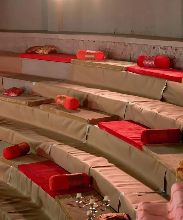 For a traditional and comfortable guest experience, I designed this baithak-style seating in an amphitheater. The red and gold cushions, along with elegant candelabras, create a regal and inviting atmosphere.