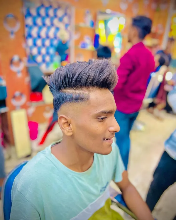 This high fade haircut is perfectly blended into a textured, voluminous top. The sharp line-up at the temple keeps the look clean and modern.