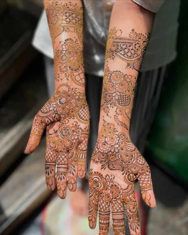 A classic, full-coverage bridal mehendi for bride Heeba. The design extends from the fingertips to the forearms, featuring a mix of floral, paisley, and geometric elements.