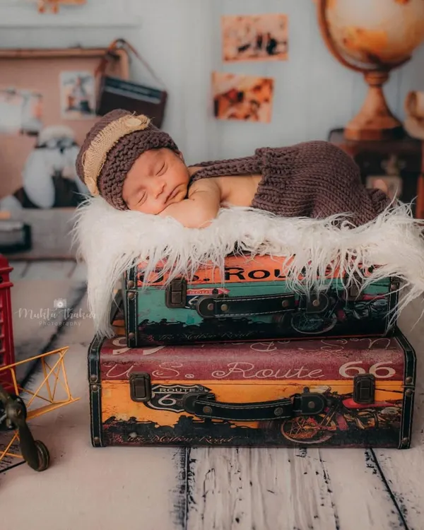 A wide shot of the 'little traveler' newborn setup. This image shows how I combine props like vintage suitcases, a globe, and a toy plane to build a complete, story-driven scene.