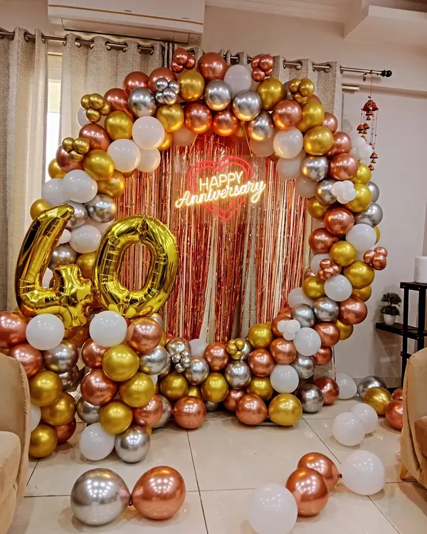 A beautiful round balloon arch in rose gold, gold, and silver for a 40th anniversary celebration. The "Happy Anniversary" neon sign and large marquee numbers create an elegant and memorable photo backdrop.