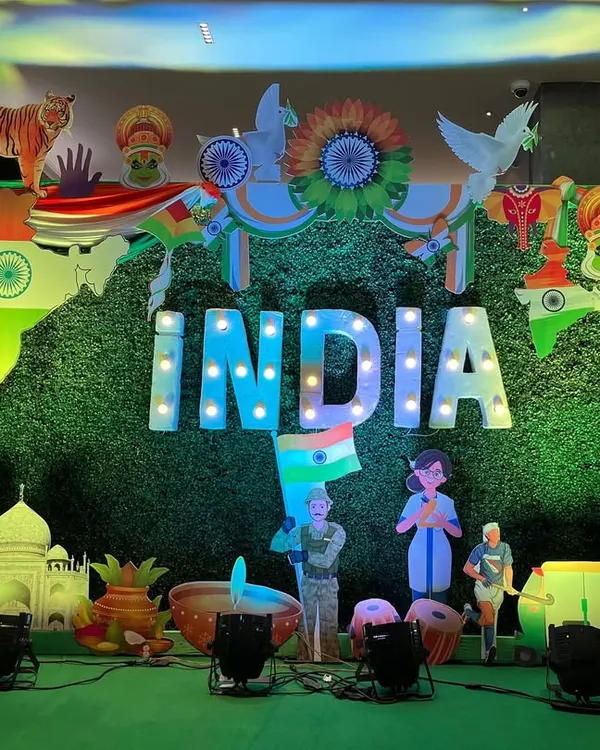 I create large-scale patriotic decor for corporate offices and community events. This Republic Day stage features a massive "INDIA" marquee sign against a green backdrop, surrounded by cutouts representing our country's diverse culture and achievements.