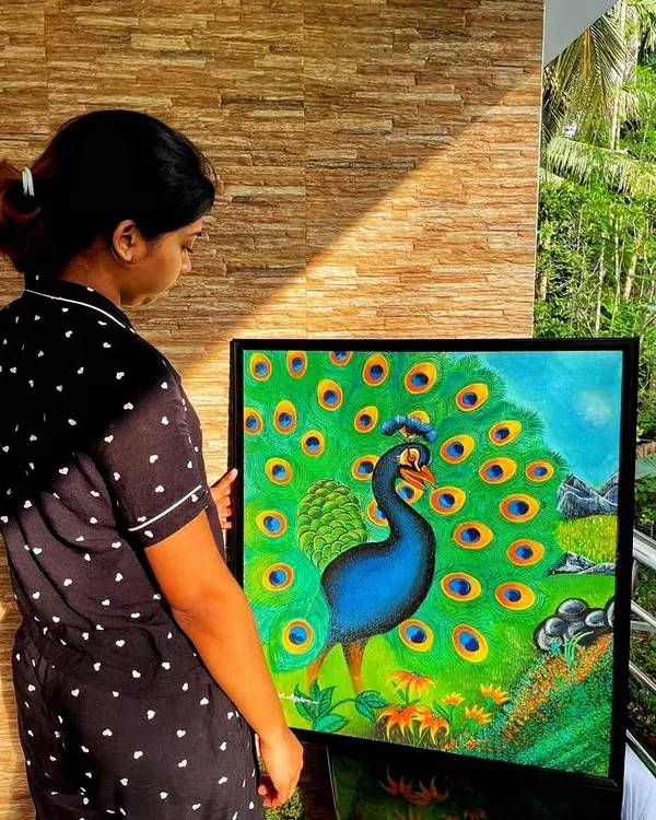 Holding my peacock painting in the sunlight. The natural light really brings out the rich greens and blues of the feathers.