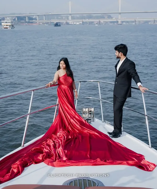 A dramatic, cinematic shot of a couple on the bow of a yacht in Goa, with the bride's long red dress flowing in the wind. This is the kind of epic, high-fashion pre-wedding photography I love to create.