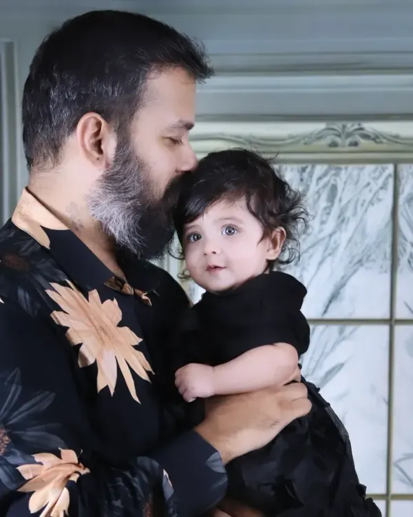 A tender moment between a father and his baby girl, as he gently kisses her forehead.