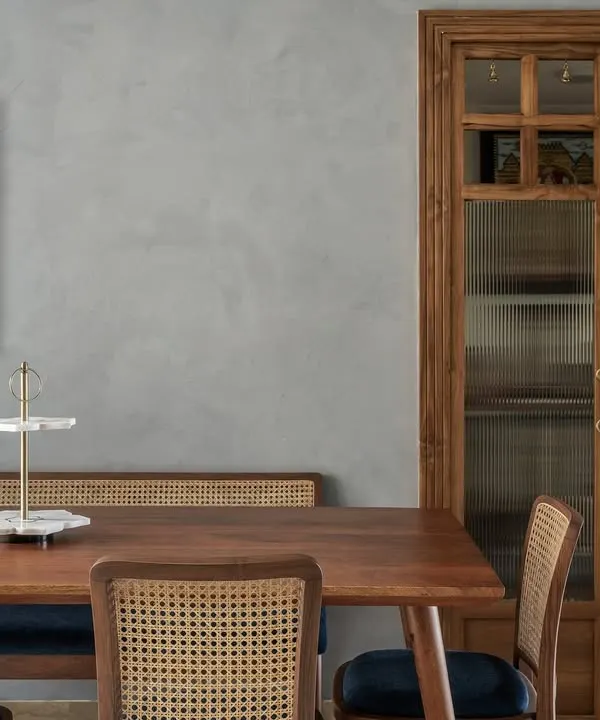 The dining room in our 'Malhar' project, showing the custom-built puja room entrance. The elegant wooden doors with fluted glass panels offer privacy while allowing light to filter through.