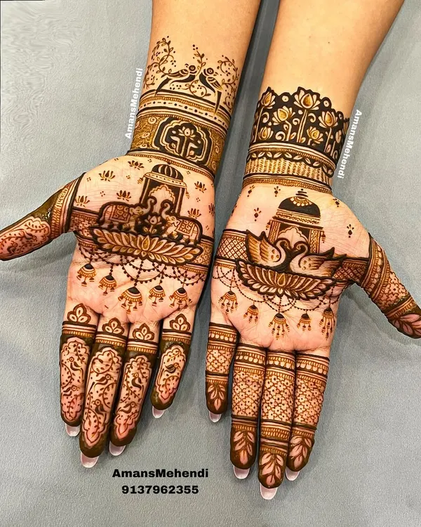 A beautiful example of asymmetrical bridal design. One hand features majestic elephants and a lotus, while the other showcases graceful swans, both incorporating traditional jharokha elements.
