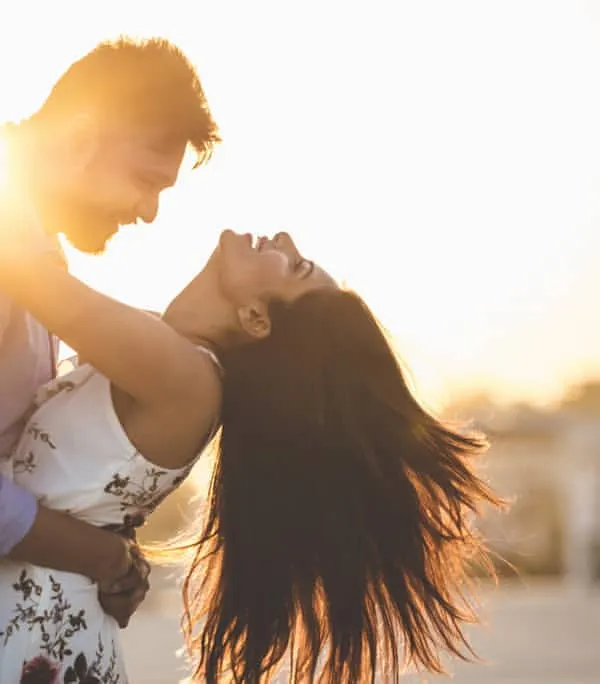 The perfect golden hour shot. This image captures the pure, unadulterated joy of a couple sharing a laugh, with the setting sun creating a warm, magical glow.