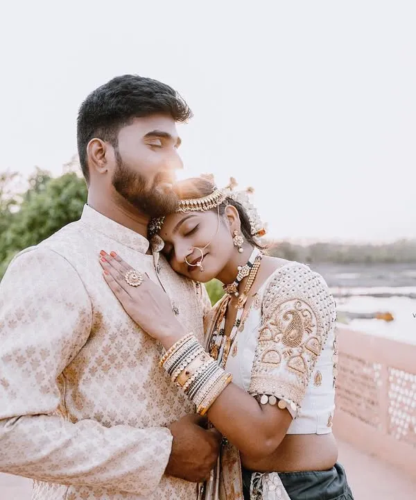 A truly romantic and serene moment from a royal pre-wedding shoot. The bride rests her head on the groom's shoulder as the sun sets behind them, creating a beautiful flare and a feeling of pure peace and love.