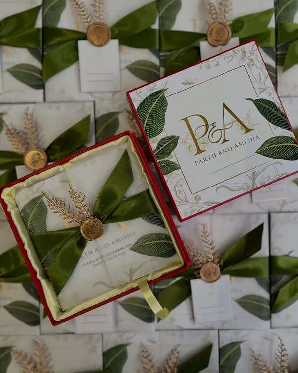This is our exquisite boxed wedding invitation for Parth and Amisha. We designed it with a lush banana leaf motif, an elegant green satin ribbon, and a custom wax seal, creating a luxurious unboxing experience that sets the tone for a sophisticated celebration.