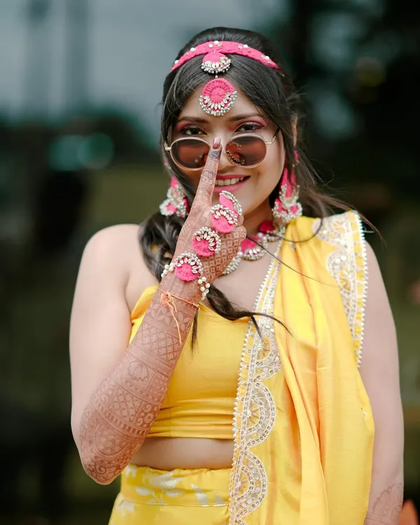 A fun and playful Haldi bride. For this look, I kept the makeup fresh and dewy with a pop of pink on the eyes, complementing her yellow outfit and floral jewelry.