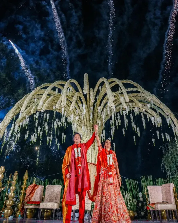 A spectacular Varmala ceremony under a custom-designed, tree-like structure adorned with flowers, culminating in a dazzling fireworks display. This is the kind of unforgettable moment I create.