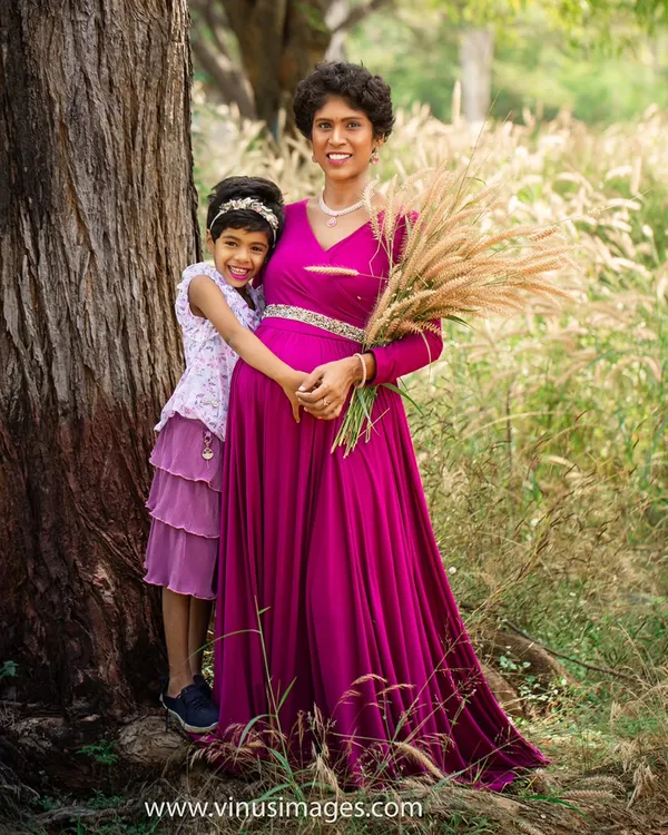 A mother and daughter share a hug in a sunlit field. This outdoor maternity photo uses the natural beauty of the surroundings to create a warm and intimate portrait.
