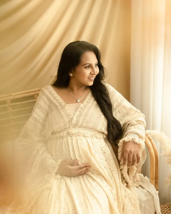 A quiet, contemplative moment for the mom-to-be. The soft, natural window light and boho decor create a peaceful setting for this solo maternity portrait.