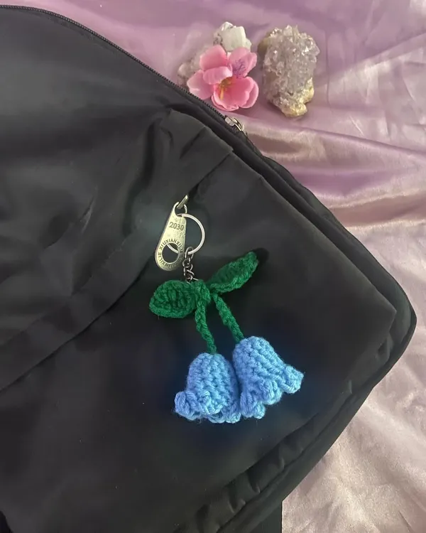 A handmade bluebell flower charm clipped onto a backpack zipper. I love how the blue pops against the black.