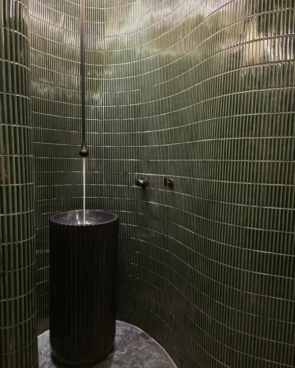 I'm not afraid of a little drama, and this powder bathroom is proof. The curved wall with deep green, textured tiles and a sleek pedestal sink creates a moody, unforgettable statement.