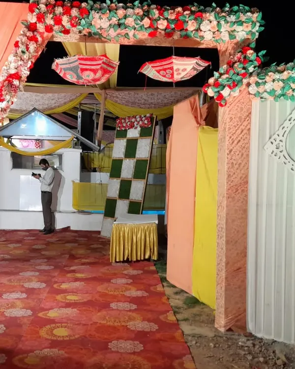Your guests' first impression matters. We design beautiful and welcoming entrances, like this one featuring a colorful floral arch, traditional decorative umbrellas, and flowing drapes to set a festive tone for the wedding celebration.