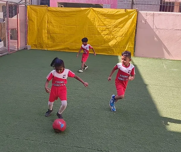 Action in full swing! A young player focuses intently on dribbling the ball during a practice match. Our classes are designed to build ball control and confidence in game-like situations.