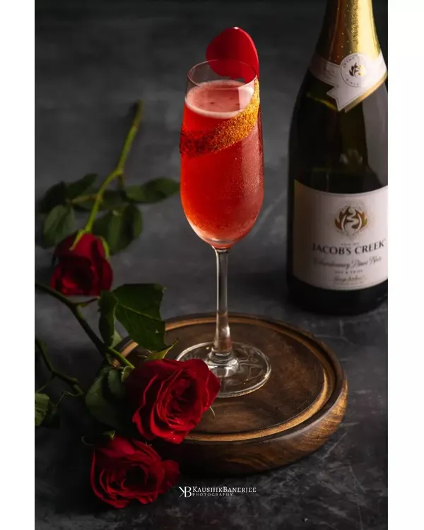 A romantic and elegant shot for a champagne cocktail. The deep red of the drink is complemented by fresh roses, creating a perfect mood for special occasions. The lighting is focused to catch the bubbles and the rich color.