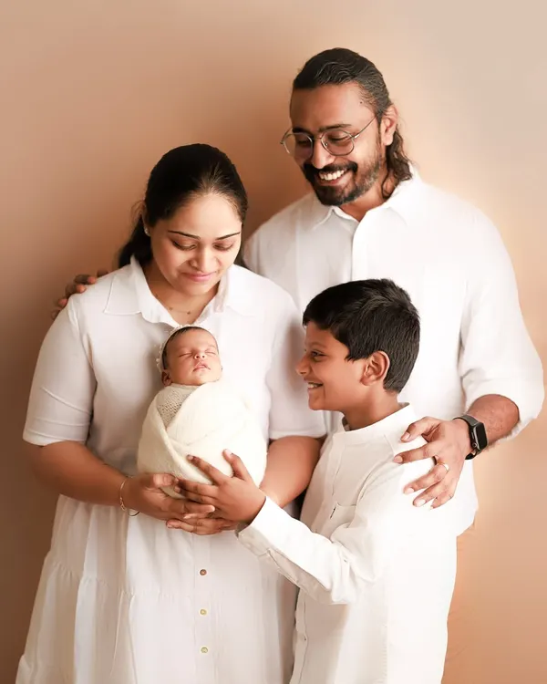 A family of four, full of smiles. The older brother looks at his new baby sibling with so much love and pride. Capturing these sibling moments is truly special.
