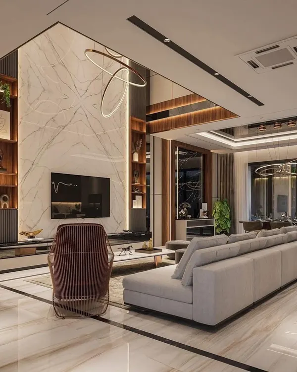 This double-height living room is the epitome of grandeur. We used a floor-to-ceiling marble-finish panel for the TV wall, flanked by wooden shelving units, to draw the eye upward and emphasize the scale of the space. The design creates a luxurious, open, and impressive area for hosting and relaxation.