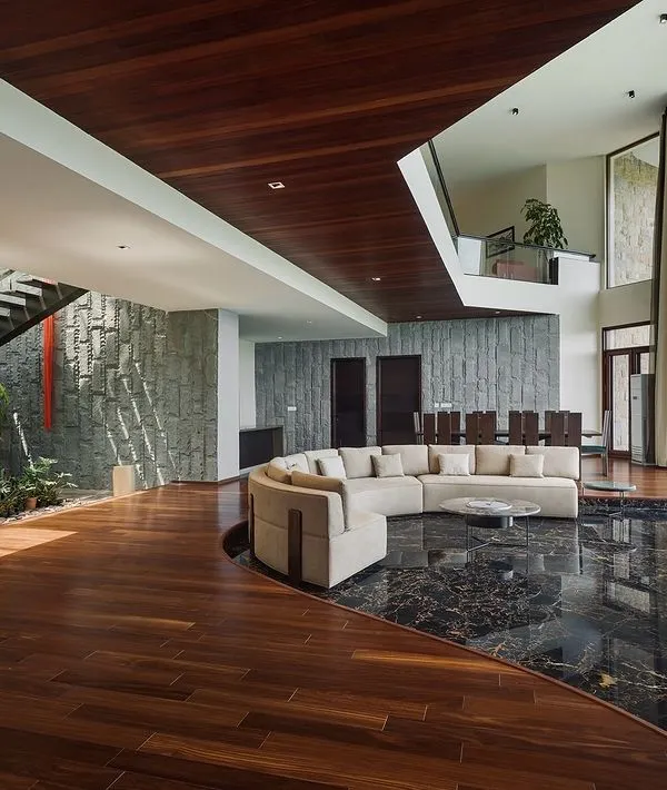 We designed this expansive living area to be a sanctuary that embraces its natural surroundings. The double-height glass walls dissolve the boundary between indoors and out, flooding the space with light and offering uninterrupted mountain views, while the combination of rich hardwood and black marble flooring defines distinct functional zones.