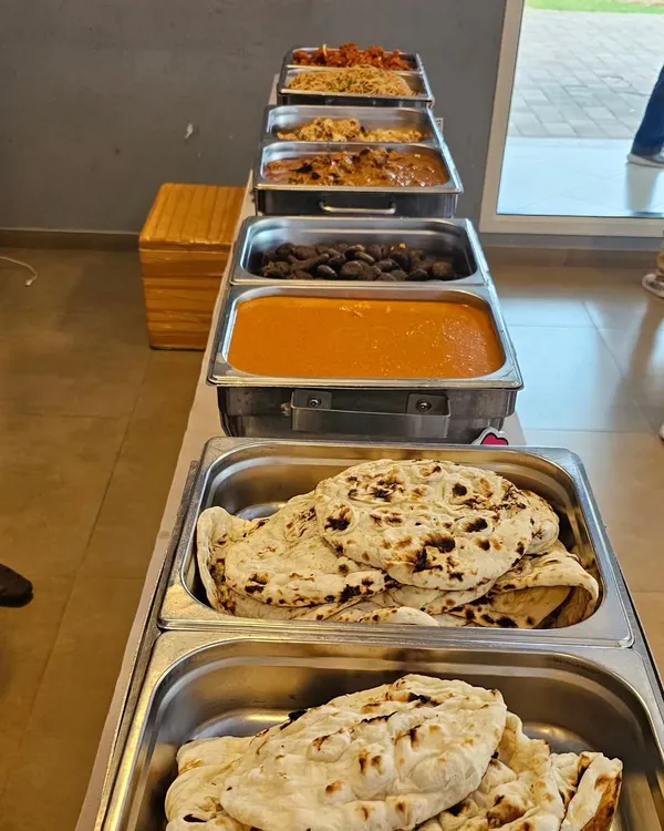A full buffet line ready for service. This spread includes a variety of Indian main courses like dal makhani and paneer, served with fresh naan bread.