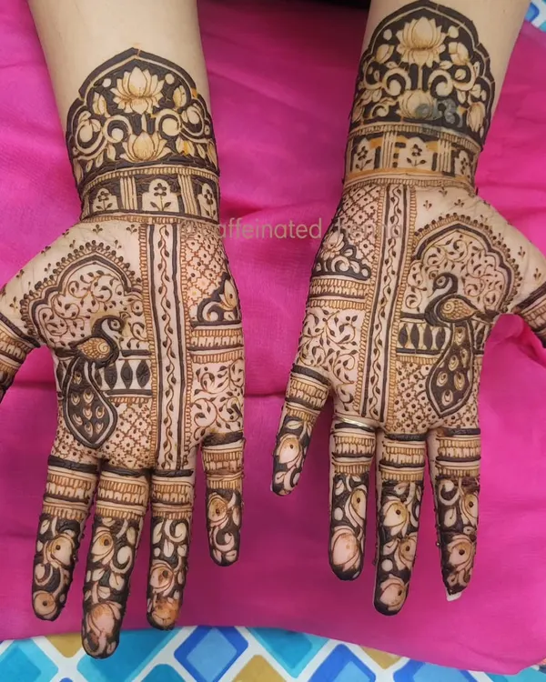 This design has such a regal feel with its combination of peacocks, lotuses, and architectural elements. It's a full-coverage look that is both bold and elegant.