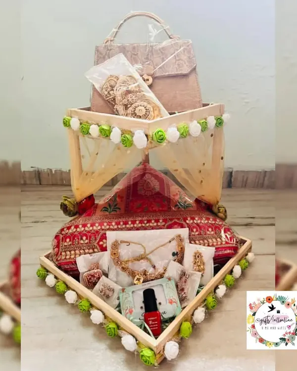 This wedding hamper was designed with a beautiful mandap theme. I used a tiered wooden tray decorated with green and white pom-poms to artfully arrange bridal jewelry, cosmetics, and other trousseau items, all wrapped elegantly in decorative netting.