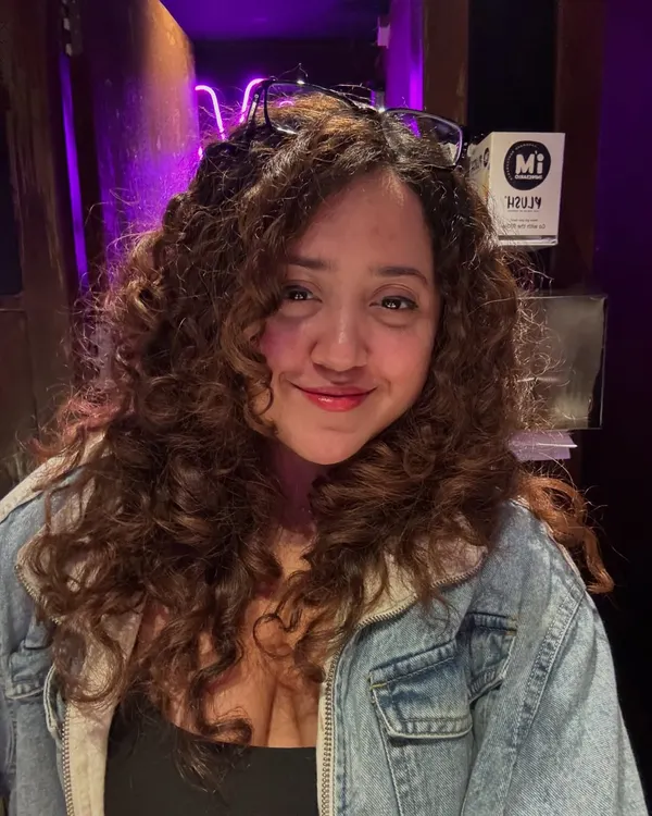 A happy client showing off her newly defined and hydrated curls after her appointment.