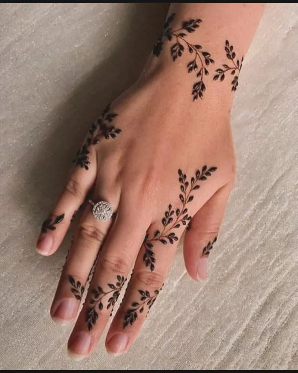 This delicate leafy vine is a perfect example of minimalist henna art. It gracefully adorns the hand and fingers, making it a chic choice for any occasion.