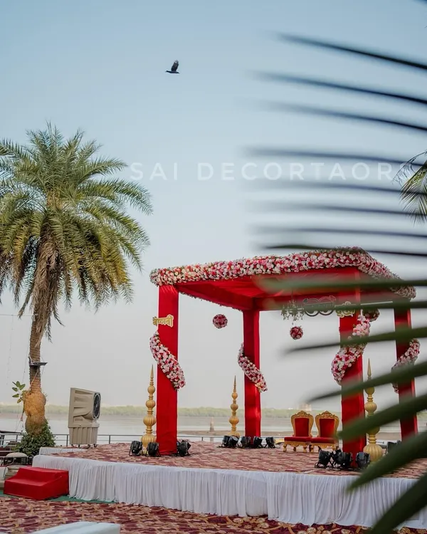 A stunning red vidhi mandap set up right by the water. This open-air design allows the natural beauty of the location to be part of your ceremony, creating an unforgettable experience.