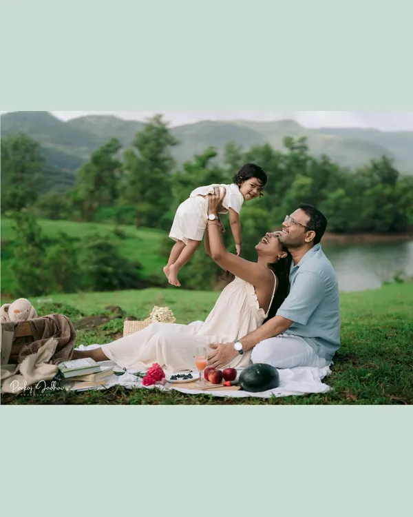 A moment of pure, high-flying joy! The mother lifts her son into the air during their family picnic, his happy face framed against the beautiful green hills.