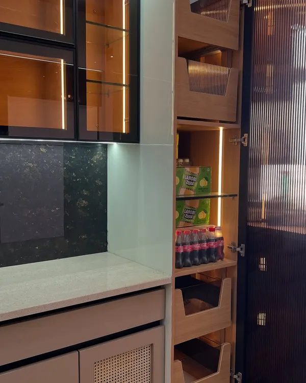 This tall unit combines a pantry with open shelving and pull-out wooden baskets. The integrated lighting ensures you can always see what you have, even at the very back.
