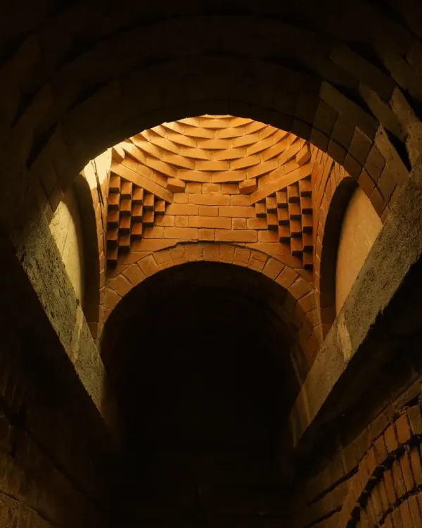 Light streams through the oculus of this intricate brick dome, creating a dramatic play of light and shadow on the corbelled geometry below. This is architecture as an experience.
