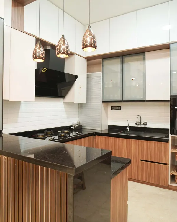 This open-plan kitchen features warm wood-finish cabinets and a breakfast bar with a black granite top, perfect for casual dining. The design is enhanced by stylish honeycomb pendant lights and white subway tile backsplash, blending classic and modern elements.