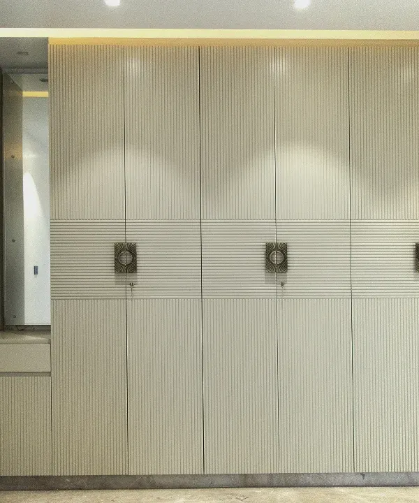 A full-wall wardrobe solution featuring fluted paneling and integrated dressing unit. The off-white PU finish creates a bright, sophisticated look while offering immense storage.