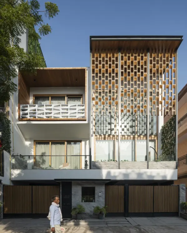The Screen House façade is a composition of open and screened volumes. The design uses a prominent wooden jaali to provide privacy for the double-height living area while allowing light to filter through, creating a dynamic and modern urban statement.