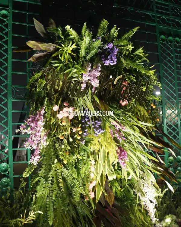 A personalized floral installation for Rohan and Ashima's wedding, with their names crafted in gold and set amidst a lush arrangement of ferns and flowers.