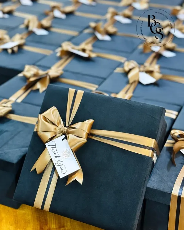 A display of sophisticated corporate gift boxes in a deep teal, finished with a perfectly tied gold satin ribbon and a "Thank You" tag. This is my signature style for making a professional statement of appreciation.