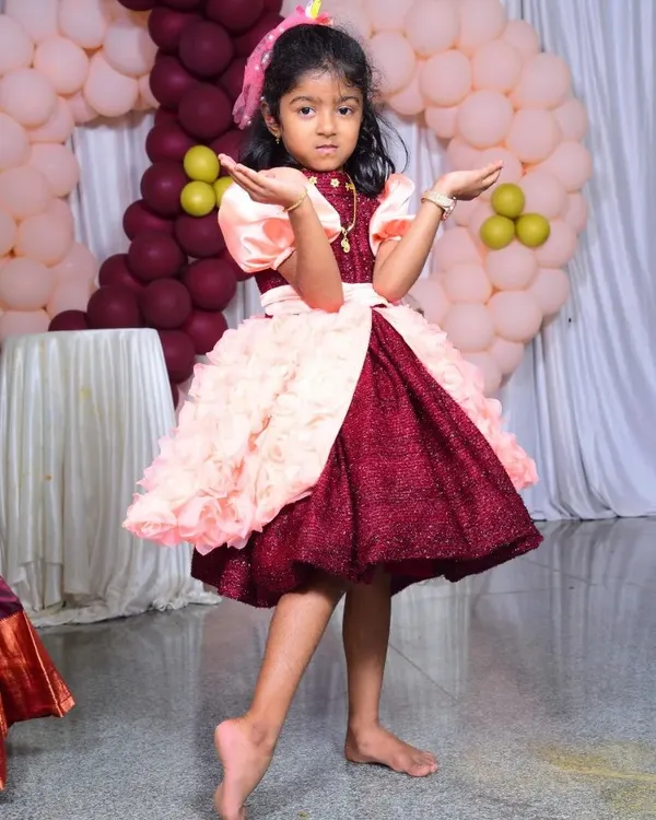 The perfect birthday dress for a little star! This custom party frock features a sparkly maroon bodice, puffed satin sleeves, and a skirt with layers of handmade fabric rosettes for a fun, textured look.