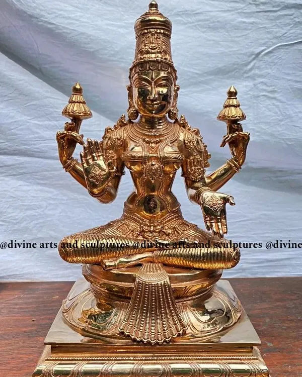This radiant sculpture of Mahalakshmi, the goddess of wealth and prosperity, is cast in polished Panchaloha. Her four hands, two holding lotuses, one in the wealth-bestowing Varad Mudra, and the other in the fear-dispelling Abhaya Mudra, are all crafted with devotional precision to capture her divine grace.