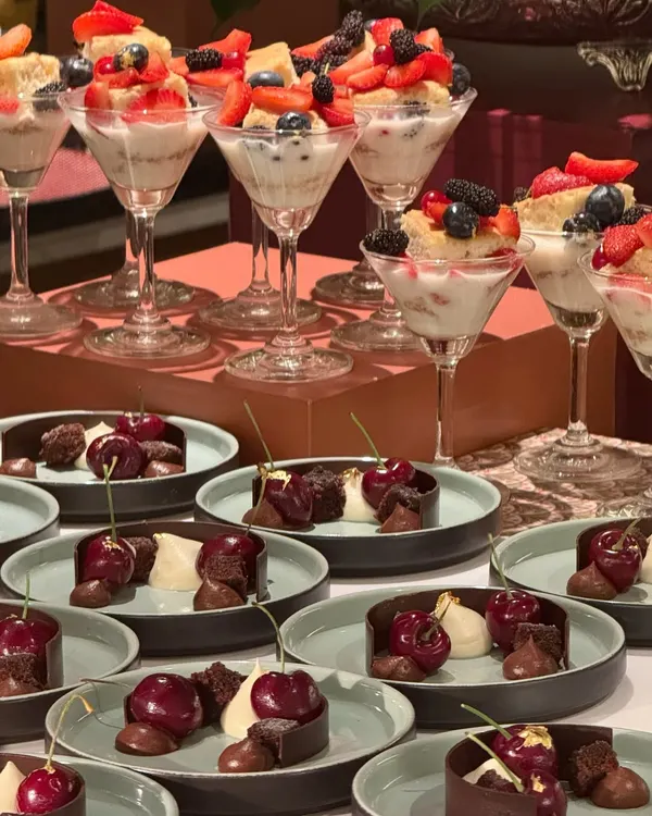 A dessert spread for those who love berries a bit too much. This table features an array of treats, from fresh berry trifles in martini glasses to rich chocolate and cherry cakes.