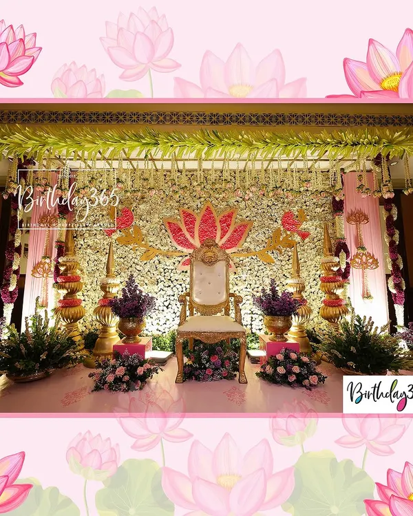 The main stage for a traditional Uttadatti ceremony, designed to feel majestic. A central throne is framed by a stunning wall of white and gold flowers, a large pink lotus motif, and elegant chandeliers overhead.