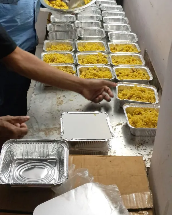 Our efficient assembly line in action, packing fresh yellow rice into aluminum containers for a large order for TATA Hospital.