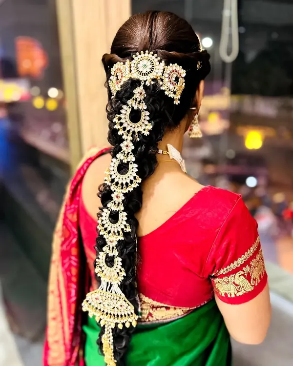 This is a traditional South Indian bridal braid, also known as a 'Jada'. I've decorated it with heavy, intricate gold-plated hair jewelry for a truly royal look.