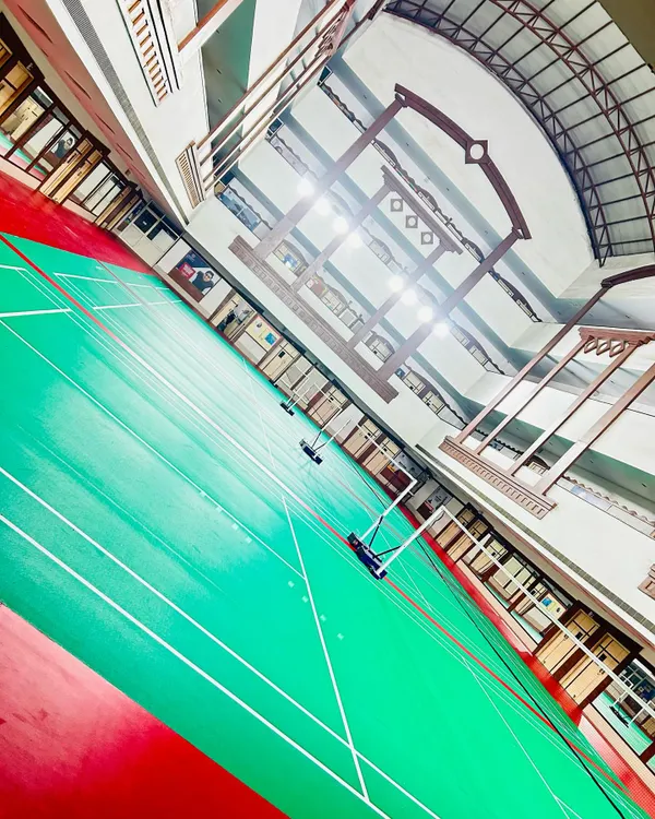 A dynamic, wide-angle view of our indoor badminton courts. The high ceiling and professional-grade flooring provide an excellent environment for competitive training.