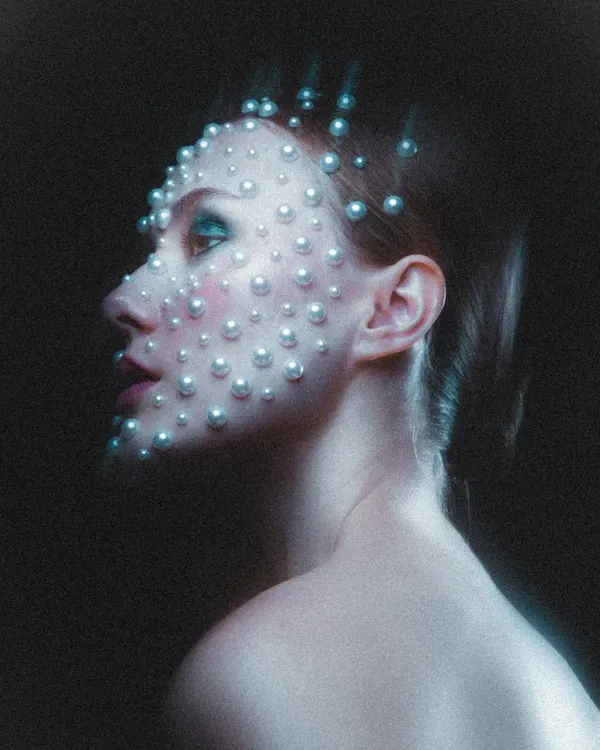 A profile view of the celestial pearl makeup, showing how the pearls catch the light and create dimension. The look was finished with a subtle blue-green eyeshadow and a soft pink lip to complement the cool tones of the lighting.